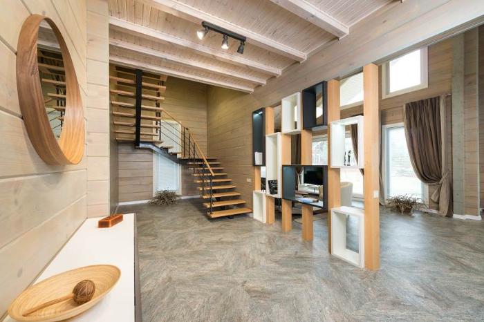 Idei de separare a holului de living cu alte materiale - hol living, oglinda rotunda, scari, televizor incorporat in structura lemn