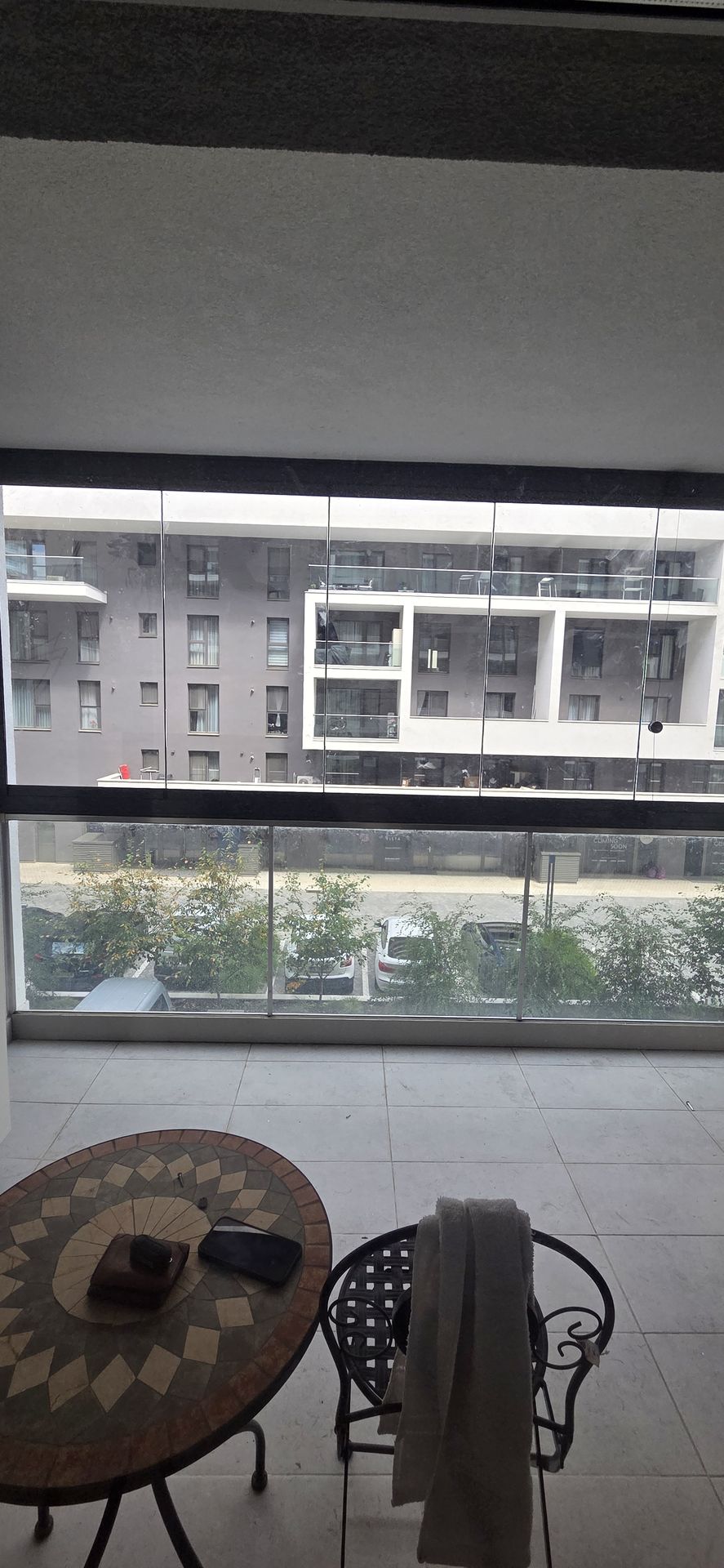 Balconul folosit ca spațiu de stat: gresie, măsuță și scaun în fața sistemului Valedo BKS închis, cu priveliștea în spate