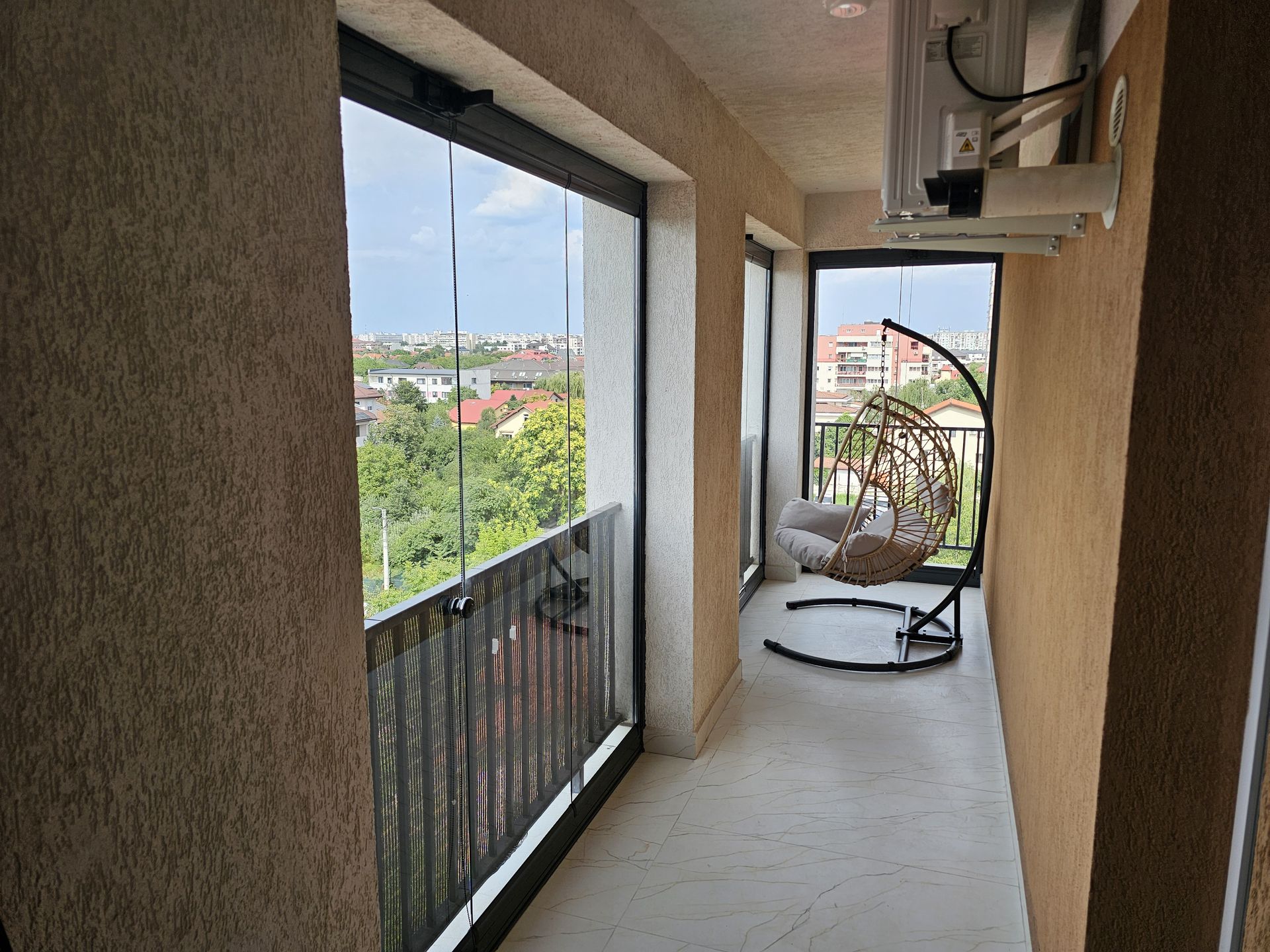Balcon pe colț închis cu panouri glisante Valedo BKS, privit în lungime, cu fotoliul suspendat în capăt — București