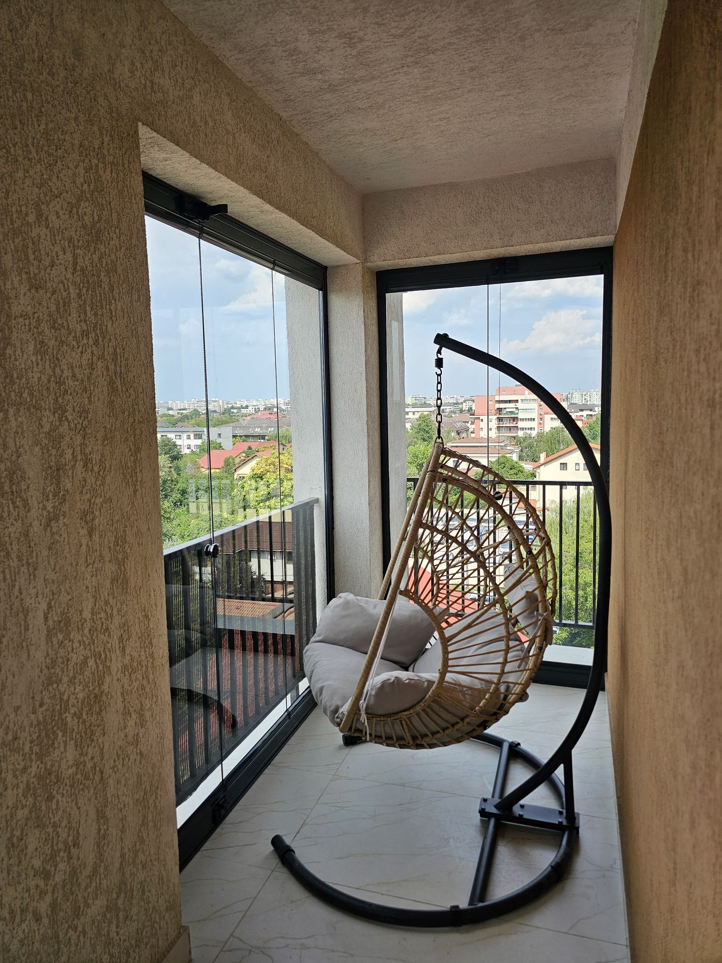 Colțul balconului cu sticlă pe două laturi și fotoliu suspendat din ratan — închidere Valedo BKS, București
