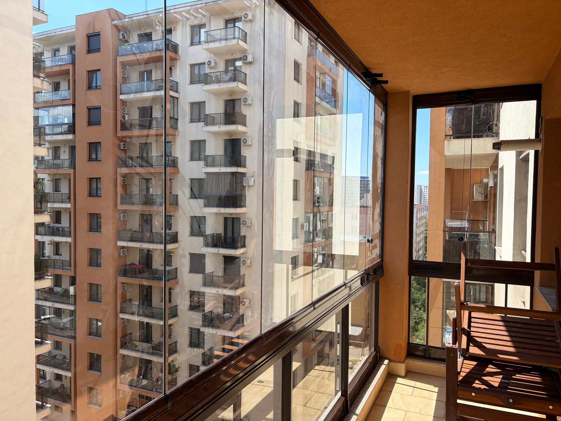 Balcon închis cu Valedo BKS în București: colțul balconului, ambele tronsoane vitrate, parapetul de sticlă și mobilierul de exterior