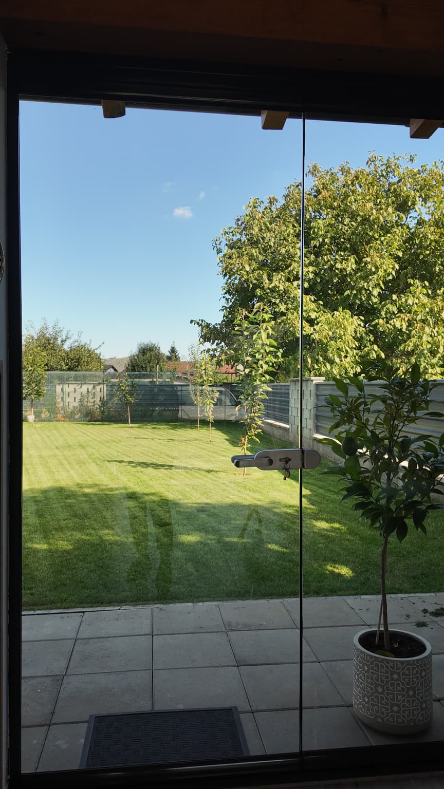 Interiorul foișorului din Bacău, cu masa și jardinierele sub tavanul de lemn și priveliștea spre grădină prin sticla Valedo BKS-T