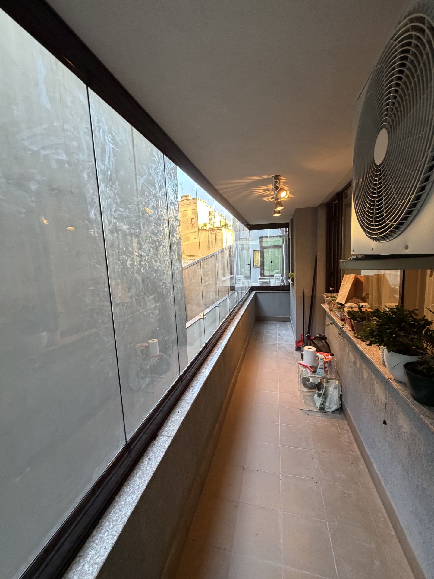 Balcon lung și îngust de apartament din București, închis pe toată lungimea cu panouri glisante Valedo BKS, în lumină caldă de seară